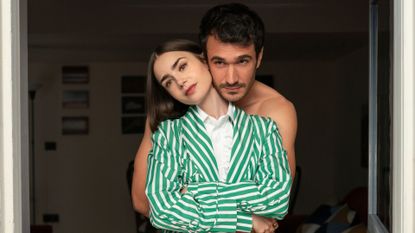 Marcello embraces Emily from behind